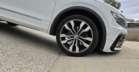  white car passing through a steep cemented driveway without a rubber kerb ramp