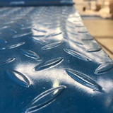 Close-up of a blue diamond-plate steel ramp surface, showing its anti-slip texture.