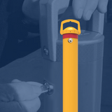 Yellow removable bollard with red reflective band, shown with a person inserting a key into the lock mechanism for secure installation