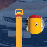 Yellow removable bollard with a red reflective band and a lock mechanism in the centre, positioned in front of a vehicle, with a close-up inset of the locking mechanism