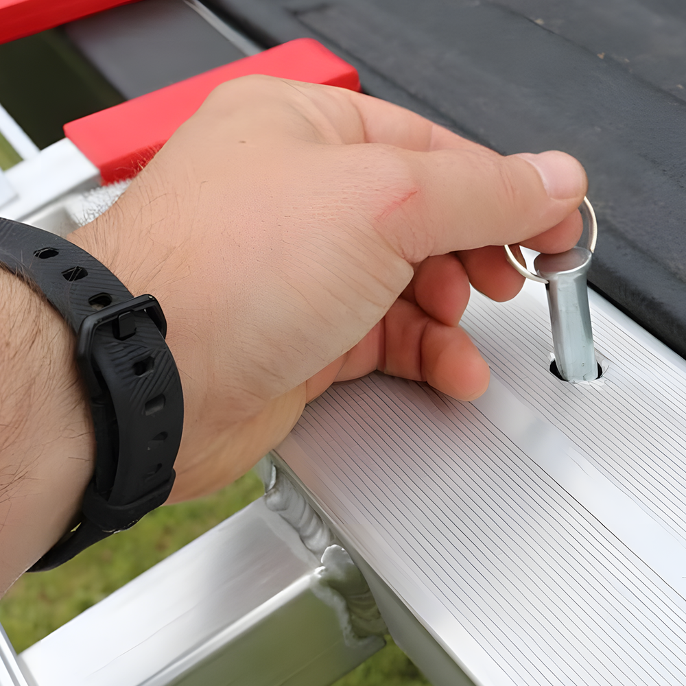 A close-up of the safety locking pin being inserted, showing how to secure the ramp in place during use.
