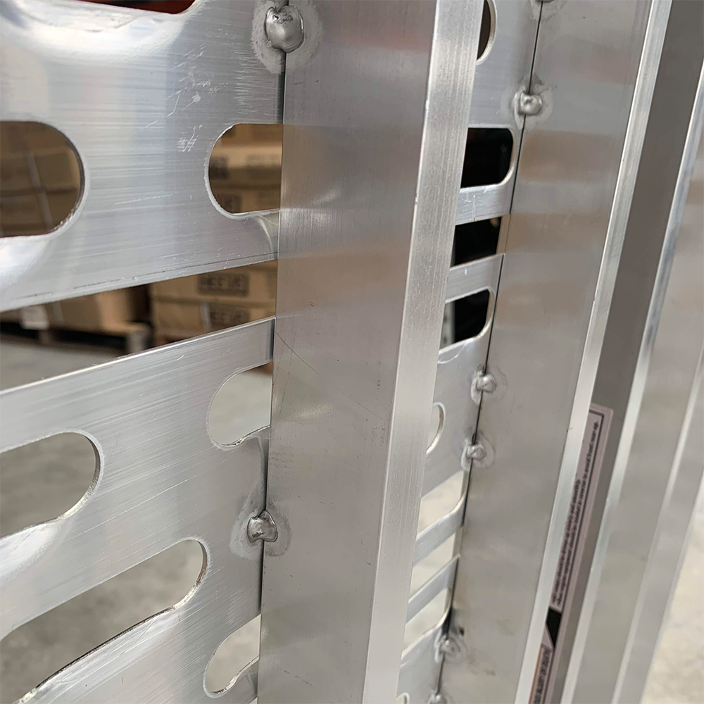 Close-up of the welded joints and construction quality of the aluminium ramp.
Ninth Photo: A vehicle parked with a dirt bike being loaded onto the tray using the ramp, highlighting the ramp's practicality for outdoor enthusiasts.