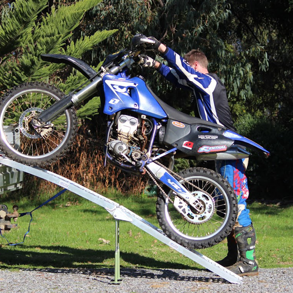 The ramp with a motorcycle being loaded onto a vehicle, demonstrating its practical application and weight capacity.