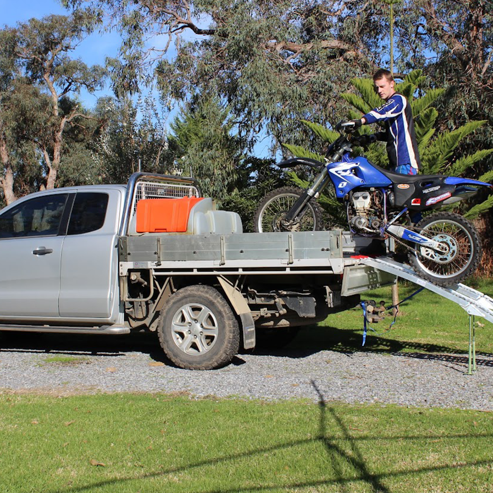 The ramp with a motorcycle being loaded onto a vehicle, demonstrating its practical application and weight capacity.