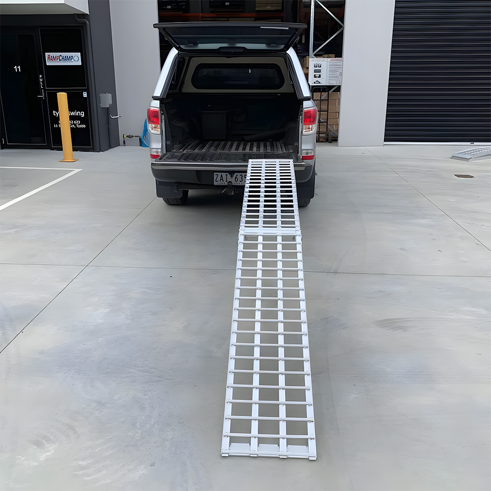 Reinforced aluminium loading ramp securely extended from the tailgate of a vehicle, ready for heavy-duty use