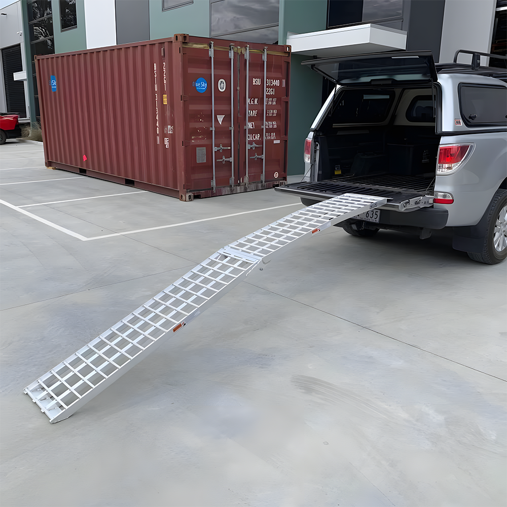 Reinforced aluminium loading ramp attached to the tailgate of a pickup truck, extended at an incline, ready for heavy-duty loading