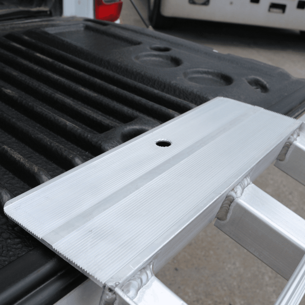 "Close-up view of the standard aluminium loading ramp securely placed on a truck bed, highlighting its durable attachment point."