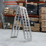 "Standard aluminium loading ramp in a warehouse setting, displayed in a folded position, ready for storage or transport."