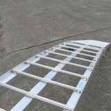 "Close-up view of a standard aluminium loading ramp with a focus on its structural design and materials against a concrete surface background."