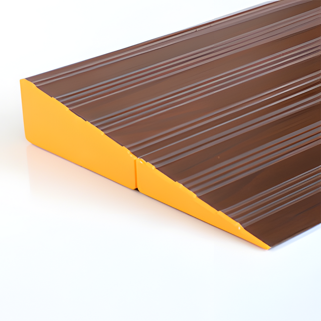 A close-up view of a brown aluminium threshold ramp with a yellow side edge, showing its textured surface.