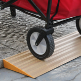 A close-up shot of a red utility cart's wheel moving over a wooden threshold ramp, showing the ramp's textured surface and yellow edge.