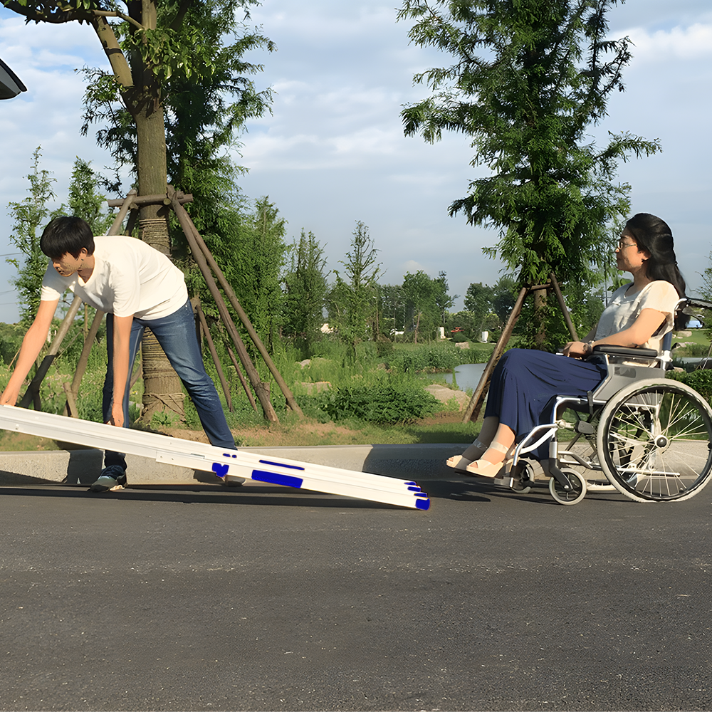 A person setting up the mobility ramp for a wheelchair user. The ramp is being adjusted to provide a smooth incline.