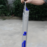 A person holding a folded aluminium mobility ramp with blue accents, demonstrating its compact and portable design.