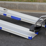 A close-up view of the extended mobility ramps placed on the ground, showcasing their textured surface and blue handles.