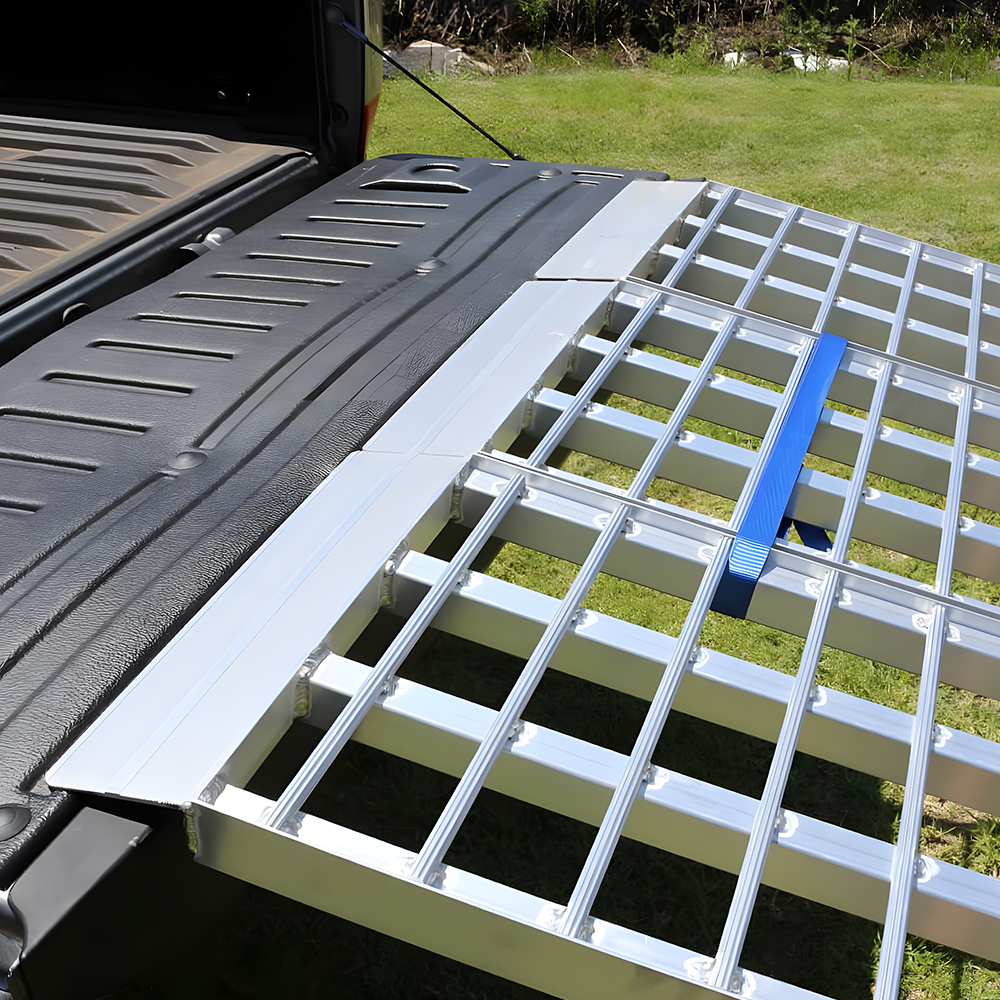 Close-up of the ramp lip resting on the truck bed, highlighting the textured end and the blue safety strap for secure connection