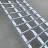 Side view of the reinforced aluminium loading ramp showcasing the evenly spaced, sturdy bars and solid construction on a concrete 