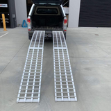 Two reinforced aluminium loading ramps positioned at the back of a vehicle, ready for loading, showcasing their sturdy design and length