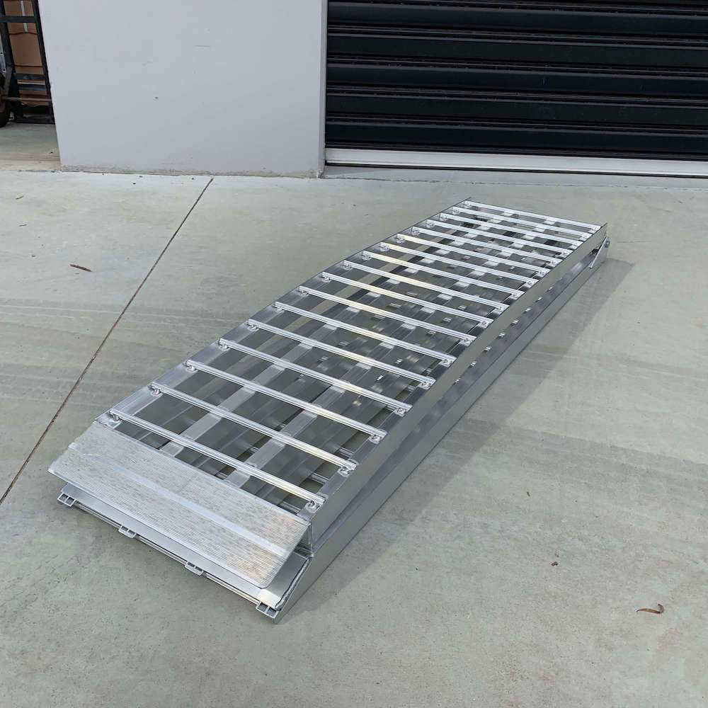 A single reinforced aluminium loading ramp folded and placed on a concrete surface, highlighting its compact and durable construction