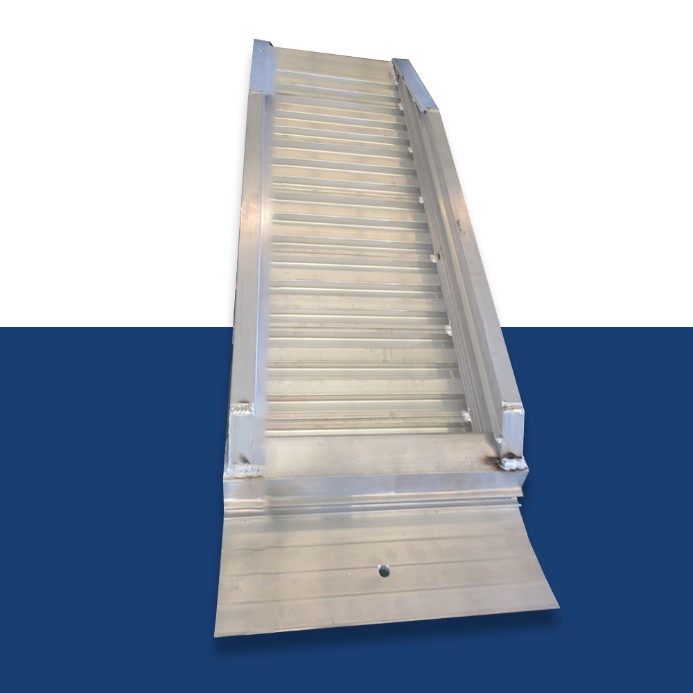 An aluminium loading ramp with ribbed traction and raised sides, positioned vertically against a dual white and blue background, with a visible pre-drilled hole at the bottom.