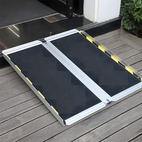 Image of a Heeve aluminium single-fold ramp placed on a wooden deck outside a door entrance, designed for wheelchair access