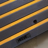 Detailed close-up of the Heeve logo on the textured surface of the kerb ramp, highlighting the durable yellow striped design and anti-slip features.