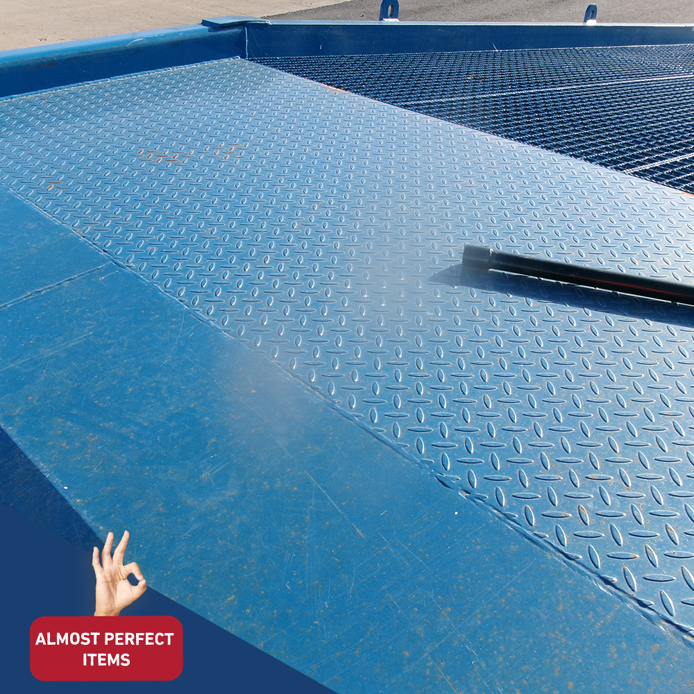 Close-up image of the Heeve Forklift Low Dock Ramp's diamond plate surface, highlighting its slip-resistant texture and durable blue powder-coated finish. A metal support bar is visible resting on the ramp. Labelled as 'Almost Perfect Items'