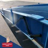 "Side view of the Heeve Forklift Low Dock Ramp, focusing on the grated surface and sturdy steel frame. A black handlebar is visible for manual adjustments, and the ramp's durable blue powder-coated finish is shown in detail. Labelled as 'Almost Perfect Items'."