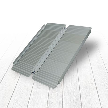 The Heeve lightweight aluminium wheelchair ramp in an unfolded position on a light wooden floor, demonstrating its compact and sleek design