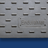 Close-up of a grey ground mat with the engraved label 'EnduraMat' from Oxford Plastics, featuring raised traction patterns