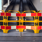 Yellow and red safety barriers blocking access to an escalator, with the barriers arranged side by side