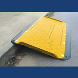 A yellow Supagrip Safekerb ramp securely placed over a kerb, providing a smooth transition from pavement to road.