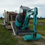 excavator moving backwards on the Sureweld 1.5-Tonne 2.4m x 390mm Rubber Series Aluminium Loading Ramps