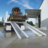 utility driver operating the backhoe over the ramp